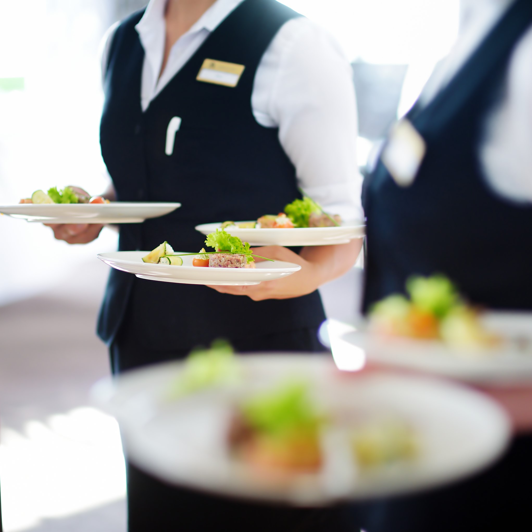 Waiter carrying plates with meat dish on some festive event, party or wedding reception