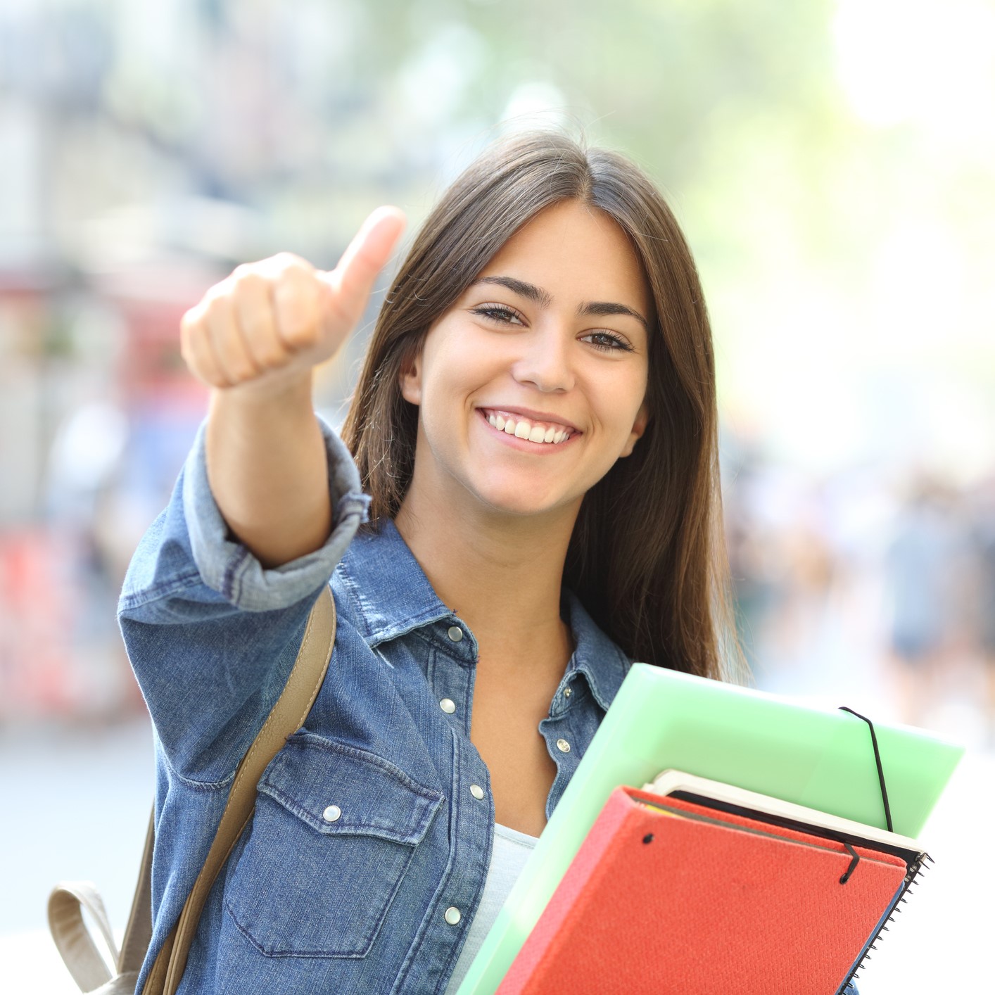 Happy student posing with thumbs up looking at you in the street